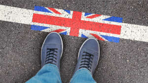 Zwei Füße vor einem Unionjack auf einer Straße