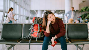 Eine junge asiatische  Frau wartet am Flughafen auf ihren Flug