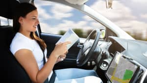 Frau liest ein Buch am Steuer eines Autos, das autonom fährt