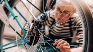 Frau putzt und repariert ihr repariert ihr Fahrrad um es fit für den Frühling zu machen