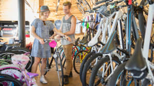 Eine frau kauft ein gebrauchtes Fahrrad in einem Shop und wird beraten