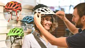Ein Verkäufer berät eine Frau beim Fahrradhelm kauf