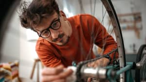 Mann reinigt eine Fahrradkette mit einem Tuch
