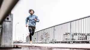 Ein Mann joggt bei tristem Winterwetter auf einem Gehweg