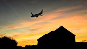 Ein Flugzeug fliegt bei Sonnuntergang über ein Wohngebiet