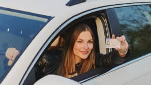 Junge Frau zeigt stolz ihren Fürherschein