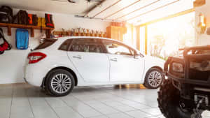 Blick in eine Garage mit einem weißen Kombi und einem Quad
