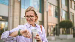 Eine Frau schaut hocherfreut auf Ihre Smartwatch