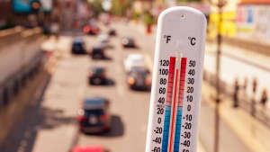 Hitze - ein Thermometer zeigt 40 Grad im Close Up im Hintergrund eine befahrene Stadtstrasse im Sommer