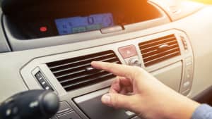 Hand an der Lüftung im Auto