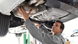 Automechaniker arbeitet am Katalysator