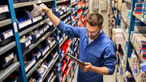 Wartungs- und Personenkonzept - Automechaniker oder Schmied mit Tablet-PC-Computer auf der Suche nach Ersatzteilen in der Werkstatt oder im Lager