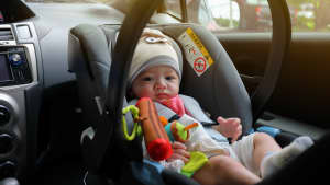 Baby sitzt im Kindersitz auf dem Beifahrersitz im Auto