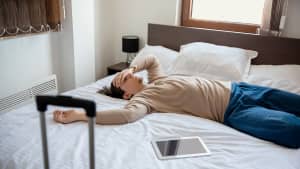 Ein Mann liegt krank auf einem Hotelbett