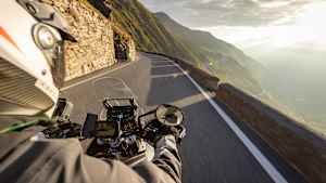 Motorradfahren in den italienischen Alpen bei Sonnenaufgang, Blick vom Lenker, dramatischer Himmel. Reisen und Freiheit, Aktivitäten im Freien