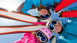 Gruppe von jungen Skifahrern mit Brillen schaut von oben in die Kamera