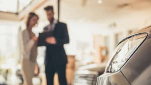Mann und Frau stehen in einem Autosalon