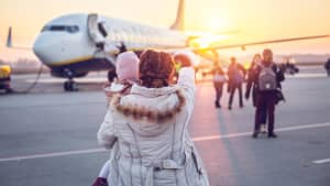 Mutter und Tochter auf einem Rollfeld mit Flugzeug im Hintergrund