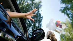 Eine Frau wirft Müll aus dem Auto