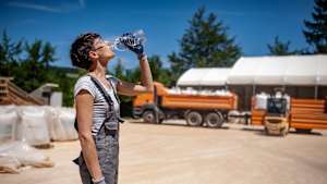 Eine Frau arbeitet in der Hitze und erfrischt sich mit Wasser