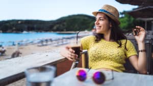 Eine Frau trinkt einen Eiskaffee am Strand
