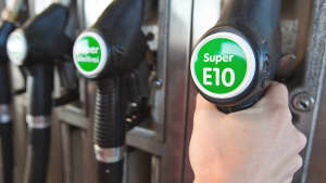 Hand greift nach Tankstutzen mit Super E10