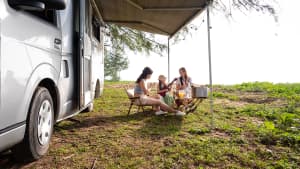 Eine Familie sitzt Gitarre spielend vor einem Wohnmobil