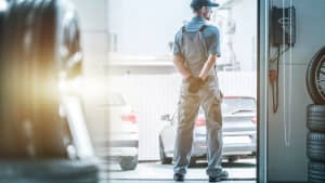 Automechaniker hält Ausschau nach Lieferanten der Ersatzteile um Auto fertig reparieren zu können