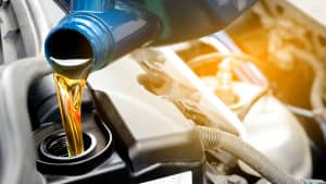 Öl lauft aus einem Kanister in einen Automotor