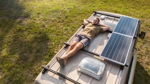 Mann liegt auf dem Rücken auf einem Wohnmobil. Spätsommerzeit mit Sonnenschein