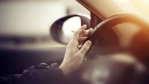 Mann mit Zigarette in der Hand fährt Auto