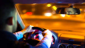 Ein Mann fährt Auto bei Dunkelheit