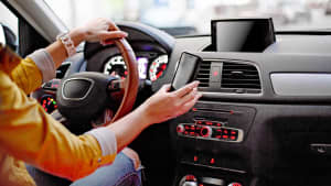 Frau hat im Auto Ihr Handy in der Hand