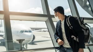 Eine Frau mit Corona Maske schaut auf Flugzeuge am Flughafen