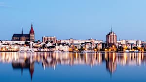 Blick auf die beleuchtete Stadt Rostock bei Abenddämmerung