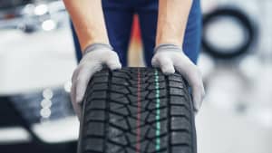 Mechaniker rollt Reifen durch eine Werkstatt