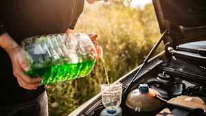 Ein mann der im Frühling Scheibenwischwasser für das Auto nachfüllt
