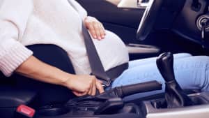 Schwangere Frau schnallt sich in Auto an