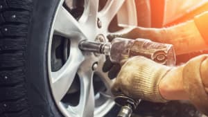 Mann mit Arbeitshandschuhen wechselt reifen