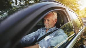 Senior sitzt hinter Steuer im Auto
