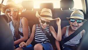 Drei Kinder sitzen nebeneinander im Auto