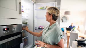 Eine Frau holt einen Joguhrt aus dem Kühlschrank