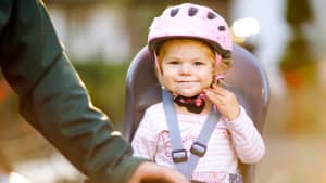 Aufnahme eines Mädchens in einem Kinderfahrradsitz, welches einen Helm trägt