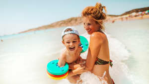 Eine Frau badet mit einem kleinen Jungen im Meer