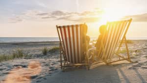 zwei leere Liebestühle am Strand bei Sonnenuntergang