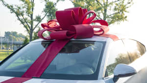 ein Auto mit einer großen Geschenkschleife auf dem Dach