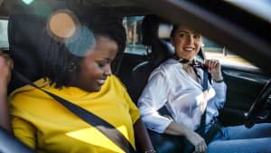 Zwei Frauen sitzen in einem Auto und schnallen sich an