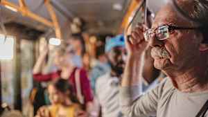 Ein älterer Mann hält sich im Bus fest