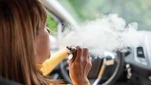 Eine Frau raucht am Steuer ihres Autos eine E-Zigarette