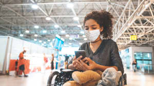 Junge Frau schaut an einem brasilianischen Flughafen auf ihr Handy